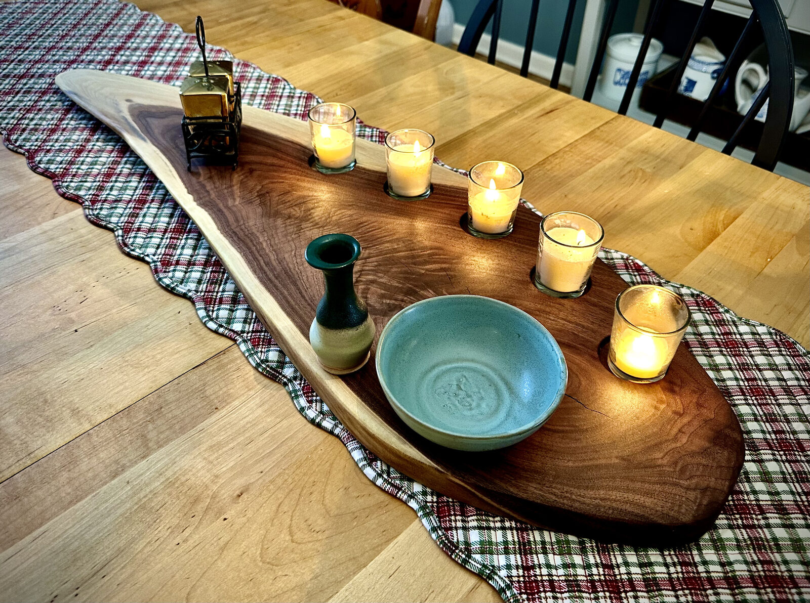 A live-edge walnut centerpiece tray with candles and pottery