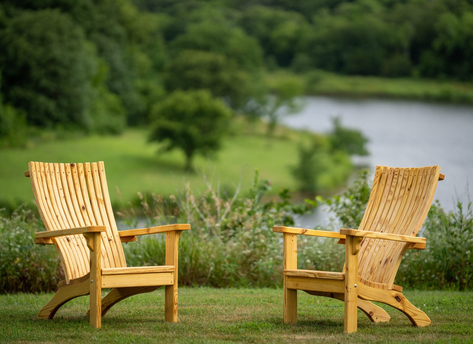 Two Briar Patch Adirondack chairs facing a pond at golden hour